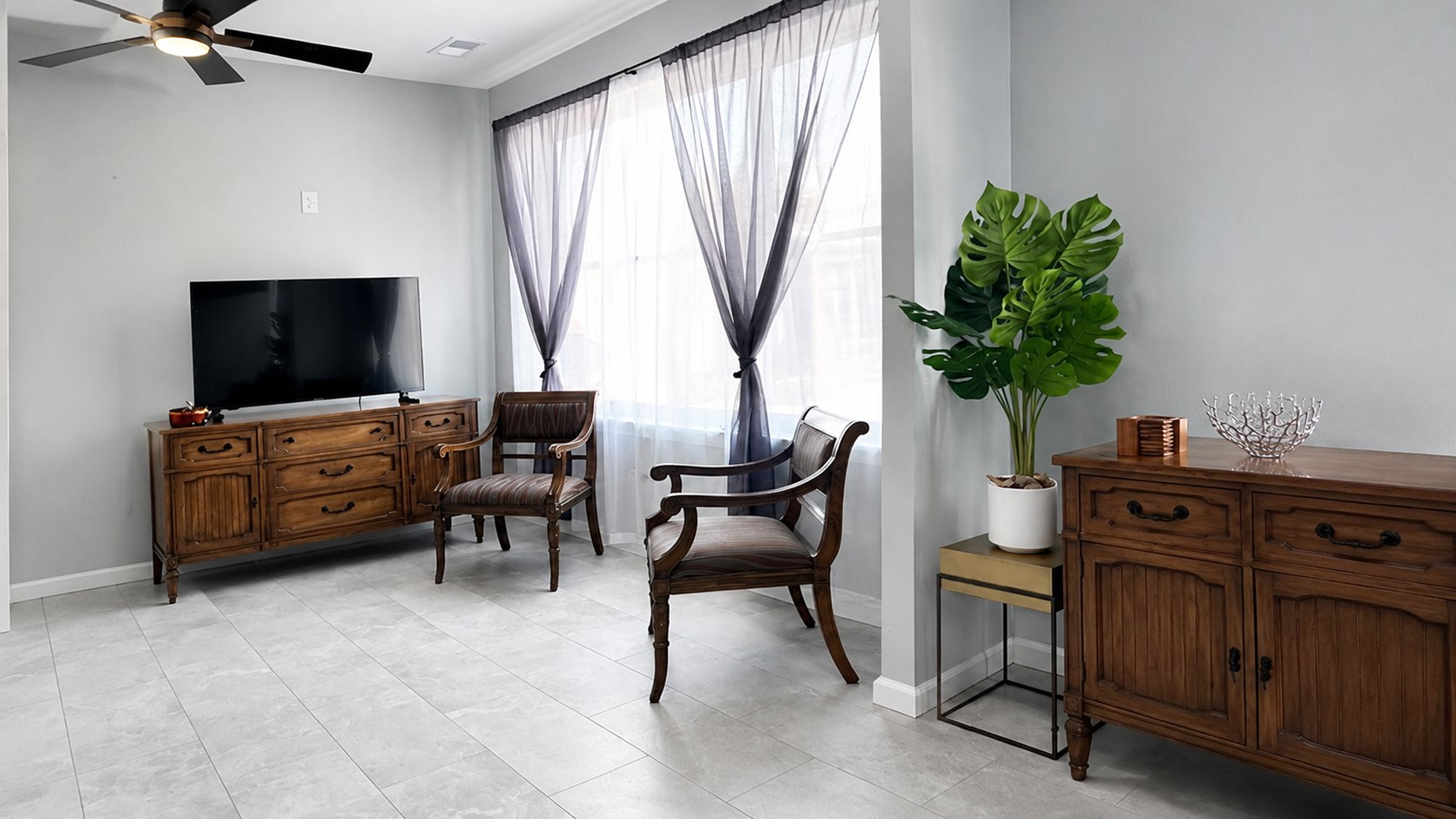 Finished upstairs residential living room with large windows and light tile flooring