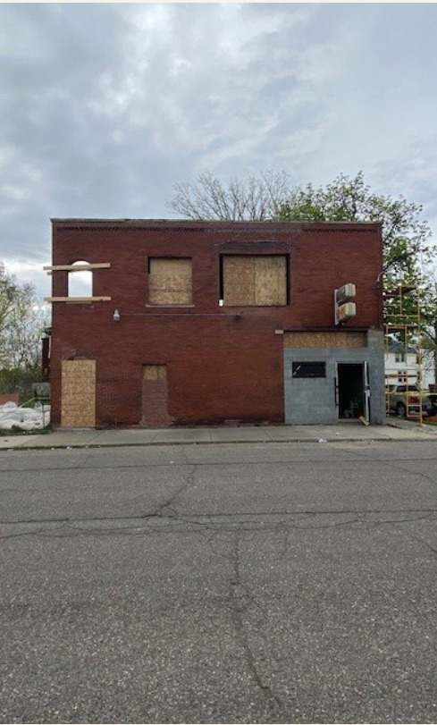 Two-story brick building with boarded windows before renovation